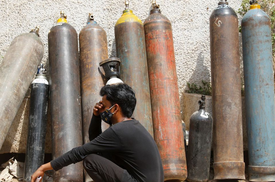 Một người đàn ông ngồi đợi sạc bình oxy tại New Delhi
