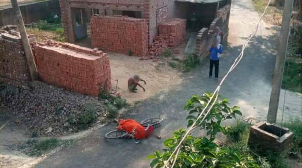Người đàn ông gầy gò ngồi thẫn thờ bên chiếc xe đạp bi ngã khi tìm cách đưa thi thể vợ đến lò hỏa táng