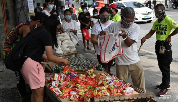 Người dân nhận lương thực miễn phí ở thành phố Quezon, ngoại ô Manila, Philippines - Ảnh: AFP