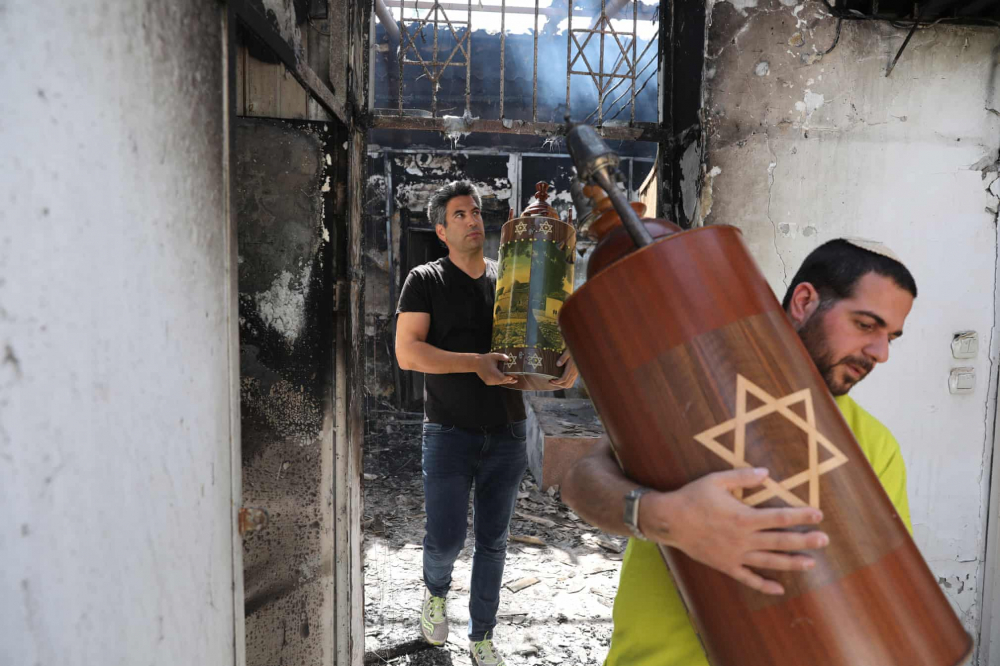 Các cư dân Israel di dời những cuộn sách Torah khỏi một giáo đường Do Thái bị đốt cháy, sau khi bạo lực qua đêm giữa cư dân Ả Rập và Do Thái ở Lod, Israel gây hậu quả nghiêm trọng.