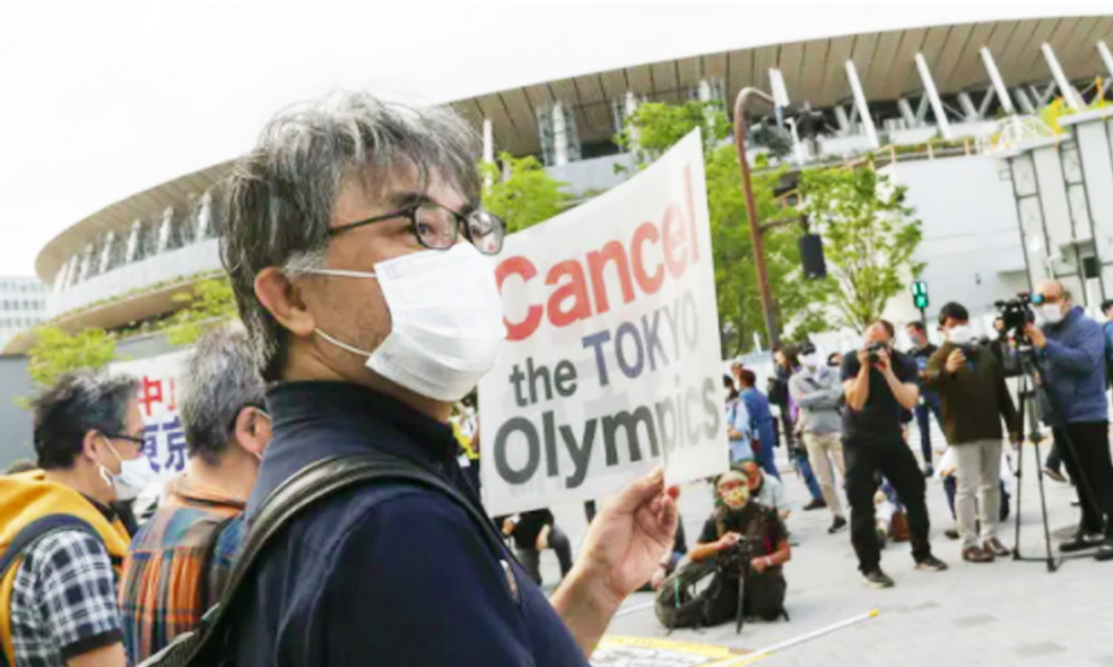 Nhiều người cầm biểu ngữ phản đối Thế vận hội Olympic Tokyo bên ngoài sân vận động quốc gia Nhật Bản