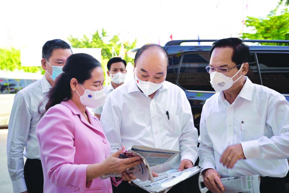 Chủ tịch nước Nguyễn Xuân Phúc cùng các ứng viên tranh thủ xem thông tin báo chí đăng tải trước khi vào buổi tiếp xúc cử tri - Ảnh: Quang Phương