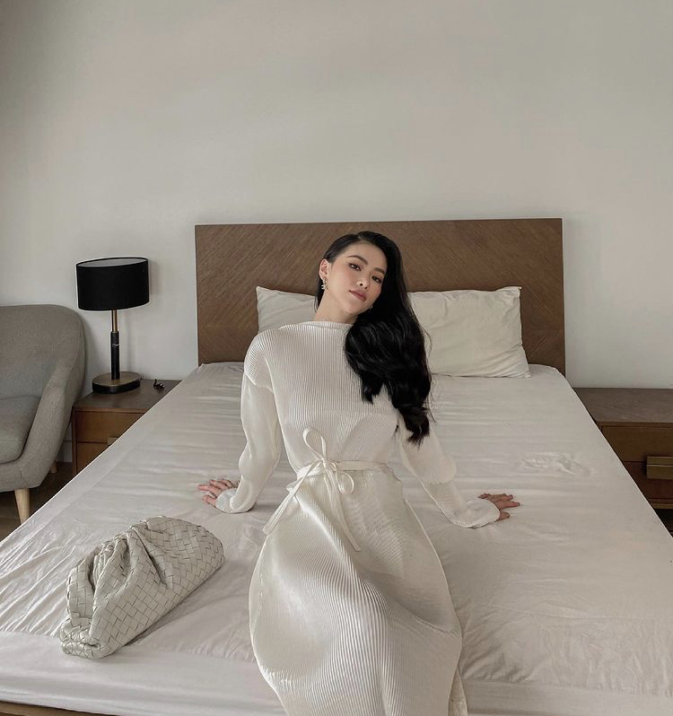 Hoa hậu Phương Khánh mặc chiếc đầm trắng tay phồng, chiết eo thanh lịch, trang điểm và làm tóc kĩ lưỡng dù chỉ chụp ảnh trên giường khi ở nhà tránh dịch.