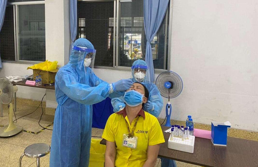 Nhân viên y tế lấu mẫu xét nghiệm tầm soát COVID - 19 trong khu chế xuất Tân Thuận 