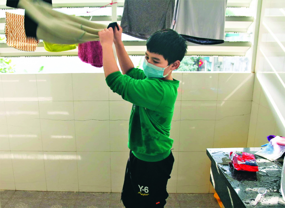 Cậu bé lớp Bốn tự giặt quần áo trong khu cách ly - Ảnh: Bộ Y tế