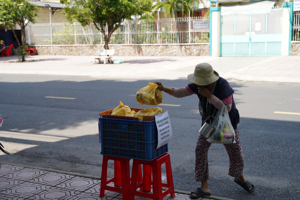 Từ ba ngày nay, trên đường Lê Quốc Hưng, quận 4, TPHCM, một doanh nghiệp du lịch đã mở quầy hàng nhỏ ngay trước trụ sở, để sẵn các túi hàng nhu yếu phẩm (mì tôm, trứng gà, cá hộp) cho người khó khăn trong giai đoạn giãn cách xã hội bằng  được đóng thành túi miễn phí với khẩu hiệu 'Nếu khó khăn xin lấy 1 phần, nếu bản ổn xin nhường cho người khác. 