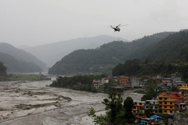 Một máy bay trực thăng của quân đội Nepal làm nhiệm vụ cứu hộ ở Sindhupalchok đang bay trên dòng sông Melamchi nước lũ tràn bờ - Ảnh: Reuters