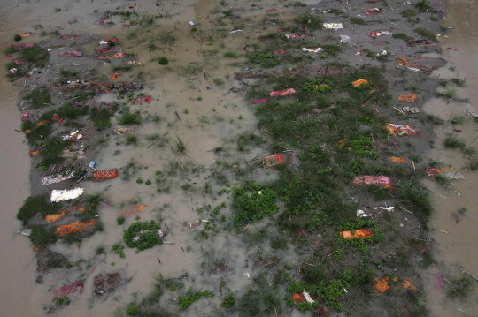 Mực nước dâng cao đã cuốn trôi đất để lộ ra những xác chết được bọc trong vải nghệ tây (Ảnh: AFP)
