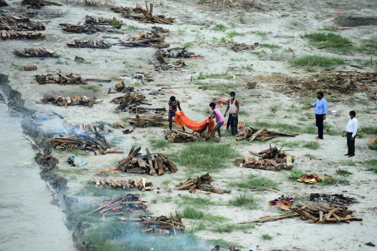 Các công nhân đặc biệt hỏa táng một thi thể được chôn trong một ngôi mộ nông bên bờ sông Hằng (Ảnh: AFP)