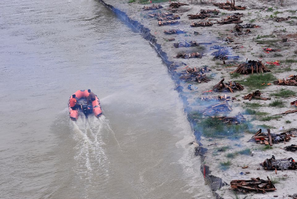 Cảnh sát cùng ngư dân địa phương dùng thuyền để đi vớt xác người trôi trên sông Hằng. (Ảnh AFP)