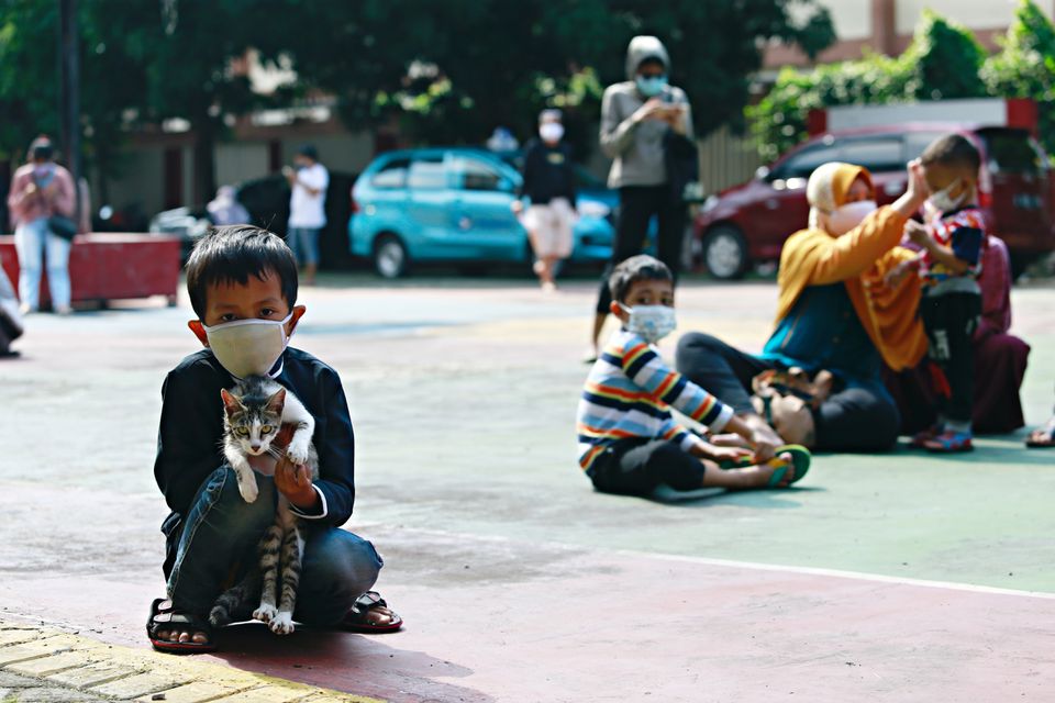 Cậu bé ôm một con mèo khi chờ lấy mẫu xét nghiệm COVID-19 trong quá trình kiểm tra hàng loạt tại một trường học ở Jakarta, Indonesia, ngày 2/7