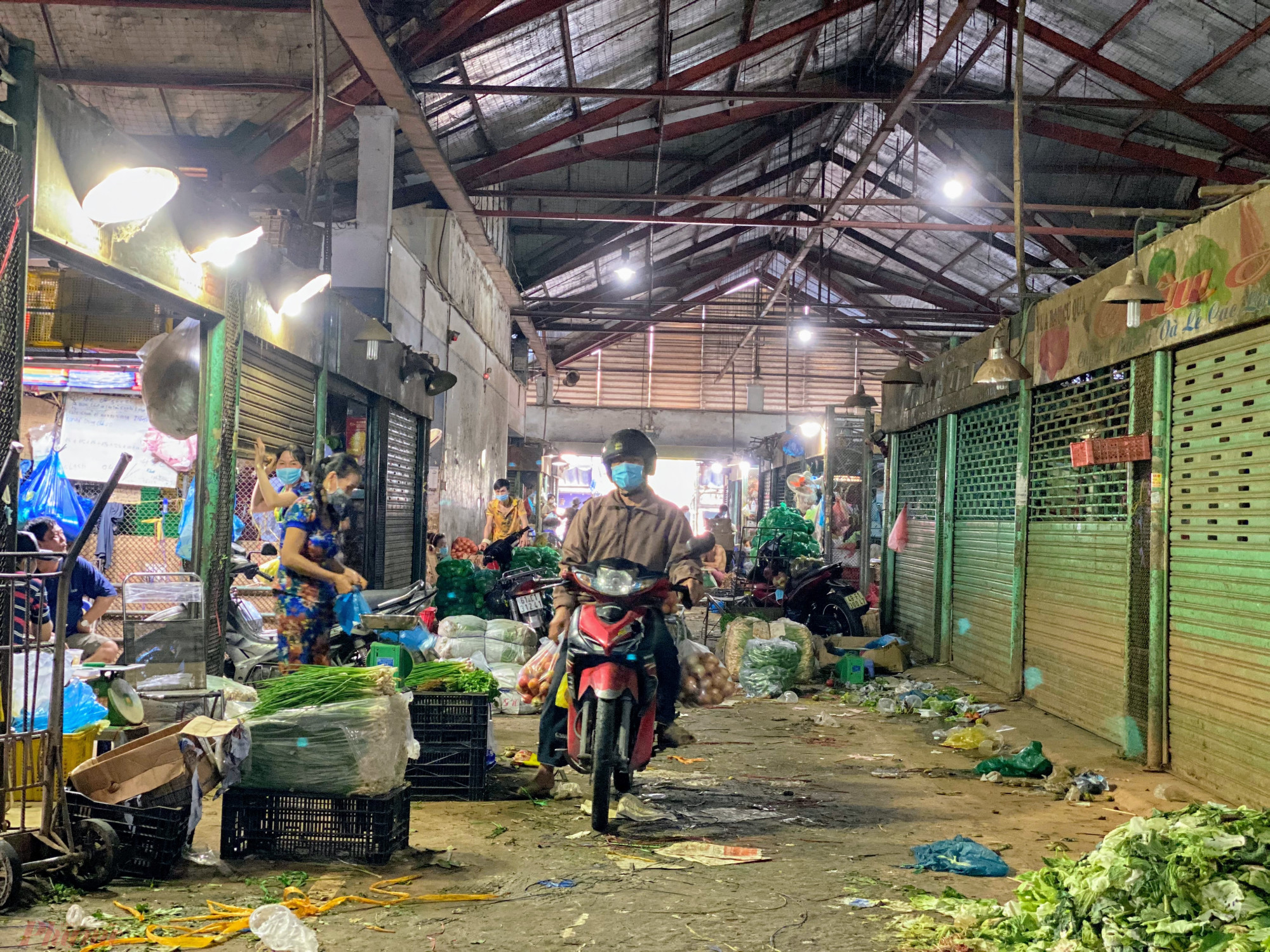 Một  người  mua  chạy  xe  máy  vào  thẳng  bên  trong  lồng  chợ  vì  chợ  đã  bắt  đầu  vắng  kháchh.