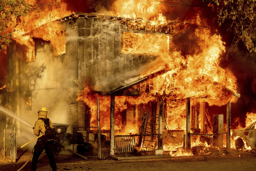 Một lính cứu hỏa phun nước trong khi cố gắng ngăn chặn Đám cháy Sugar, một phần của Đám cháy Phức hợp Beckwourth, lan sang các ngôi nhà lân cận ở Doyle, California.