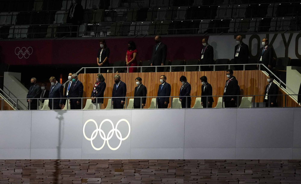 Nhật hoàng Naruhito, chủ tịch IOC Thomas Bach và các đại biểu khác đứng yên chào cờ trong lễ khai mạc