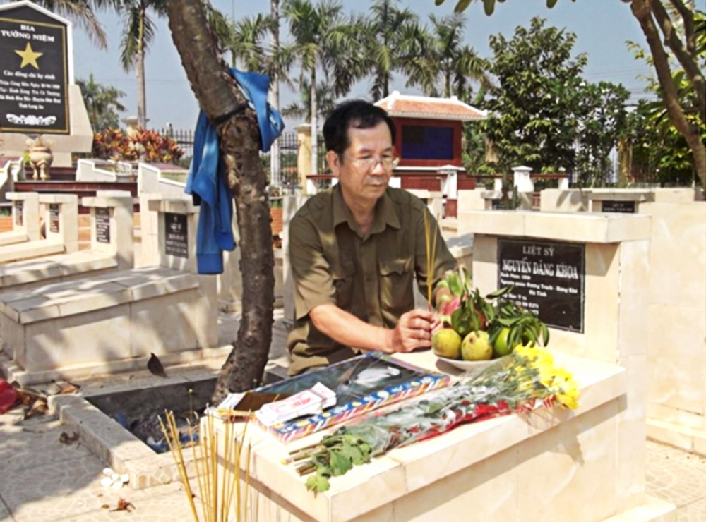 Thầy Nguyễn Sỹ Hồ thắp hương cho anh mình - liệt sĩ Nguyễn Đăng Khoa trong ngôi mộ đã được trả lại tên 