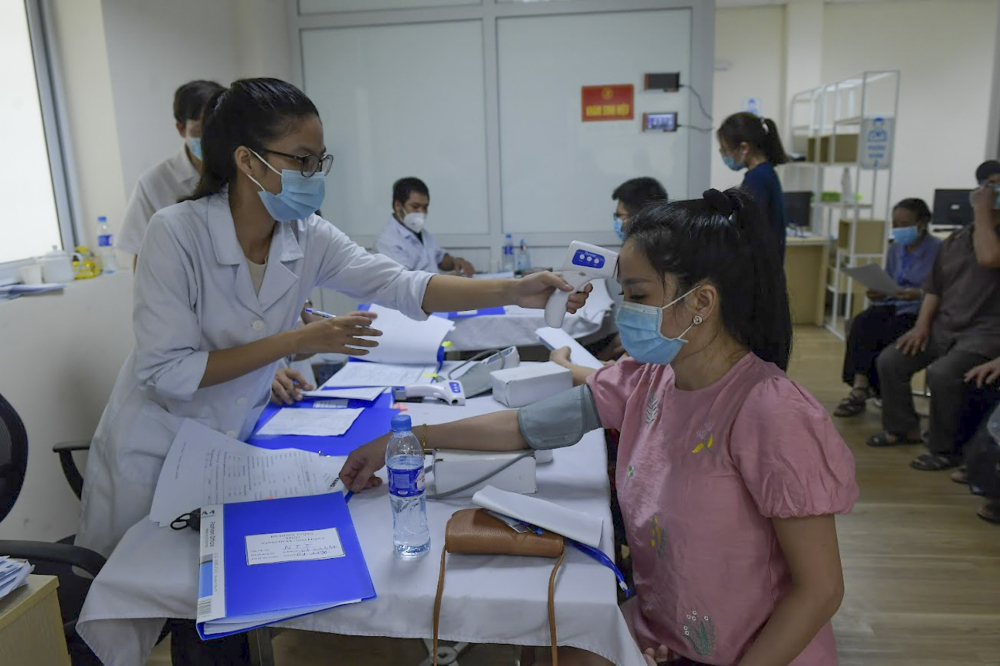 Nhân viên y tế kiểm tra sức khỏe cho các tình nguyện viên trước khi tiêm.