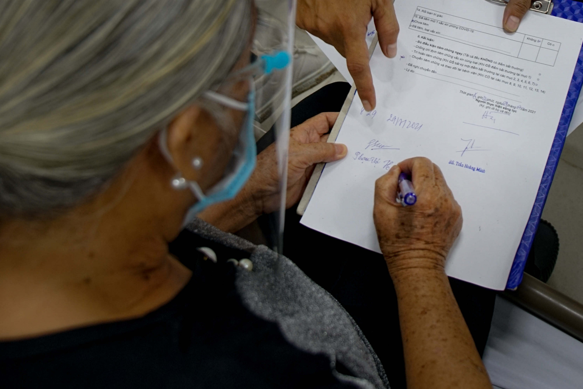 “Bác thấy ổn và khoẻ. Con thấy chữ ký đẹp không” - cụ bà 78 tuổi đùa vui lại với nhân viên y tế khi giao lại giấy ký nhận trước khi ra về.