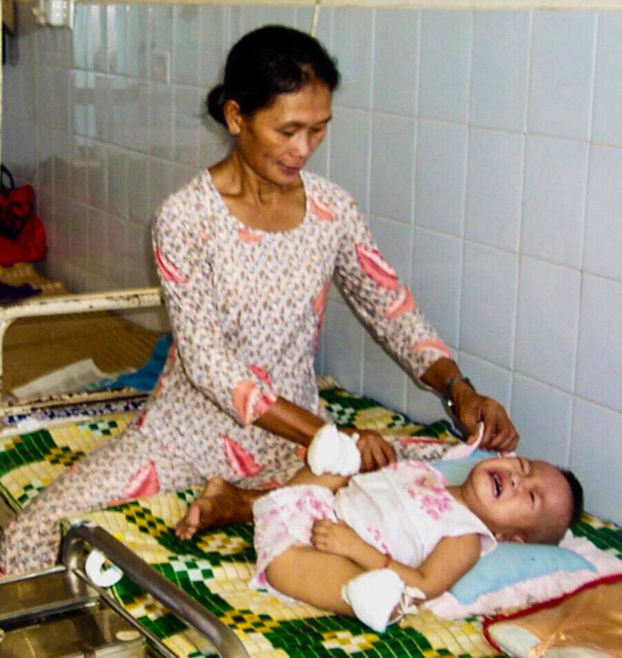 Bà Cao Thị Ba đang chăm cháu ngoại của mình trong bệnh viện Tam Kỳ, Quảng Nam - Ảnh: Shelly Shepherd