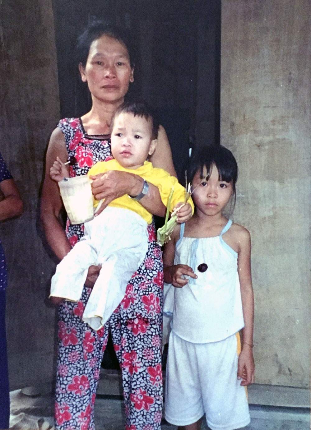 Bà Cao Thị Ba đang bế Thúy Phượng trước khi trao cho vợ chồng người Mỹ. Đứng bên cạnh là chị gái Mỹ Duyên lúc đó mới 6 tuổi - Ảnh: 
