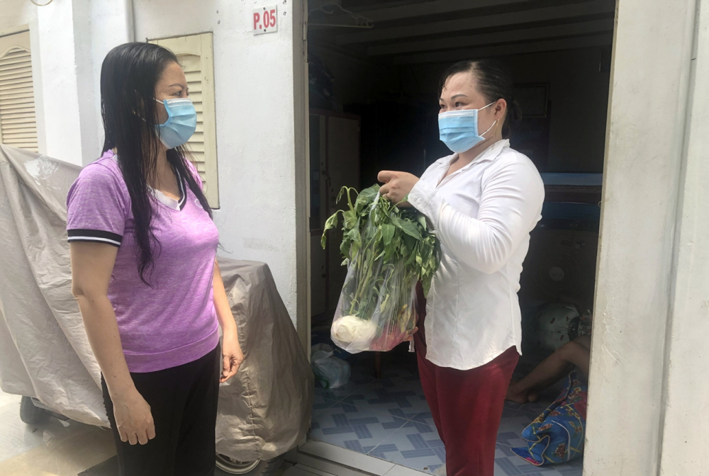 Chị Lê Thị Kim Chi (bìa trái) hỗ trợ thực phẩm và động viên vợ chồng chị Cương ở lại TP.HCM