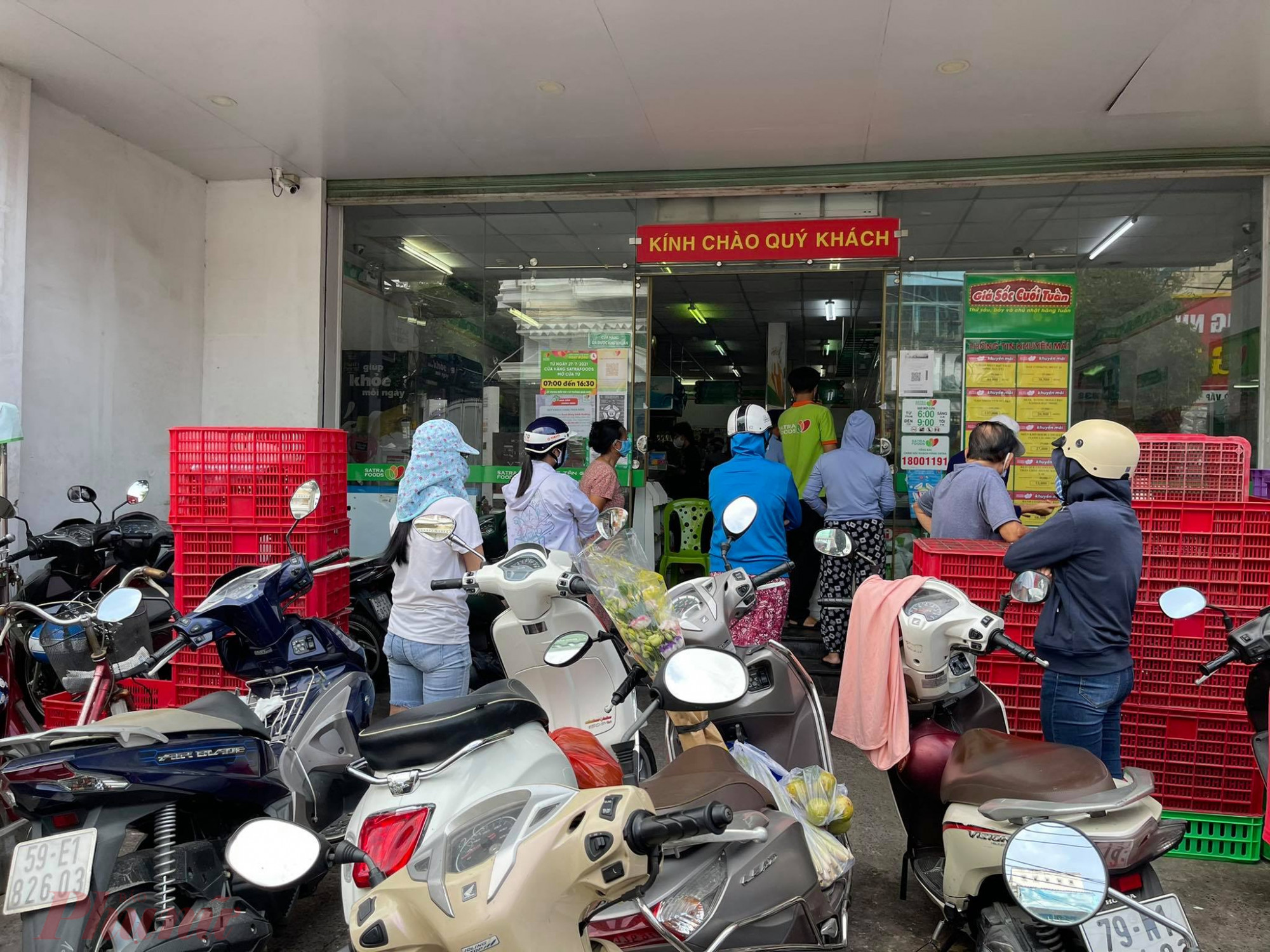 Khách xếp hàng tại cửa hàng SatraFoods Lê Đức Thọ, quận Gò Vấp. Bên trong đang có nhiều khách mua hàng, chờ tính tiền. Bảo vệ chỉ cho một khách vào khi có một khách ra.
