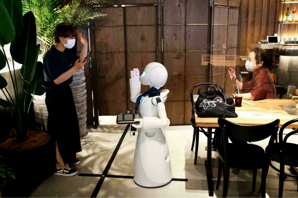 Robot của quán cà phê chủ yếu là phương tiện trung gian để nhân viên có thể giao tiếp với khách hàng - Ảnh: AFP