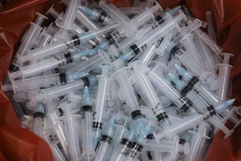 Các ống tiêm đã qua sử dụng bị vứt bỏ trong thùng sau khi chúng được sử dụng để tiêm vắc-xin phòng bệnh coronavirus (COVID-19) ở Mumbai