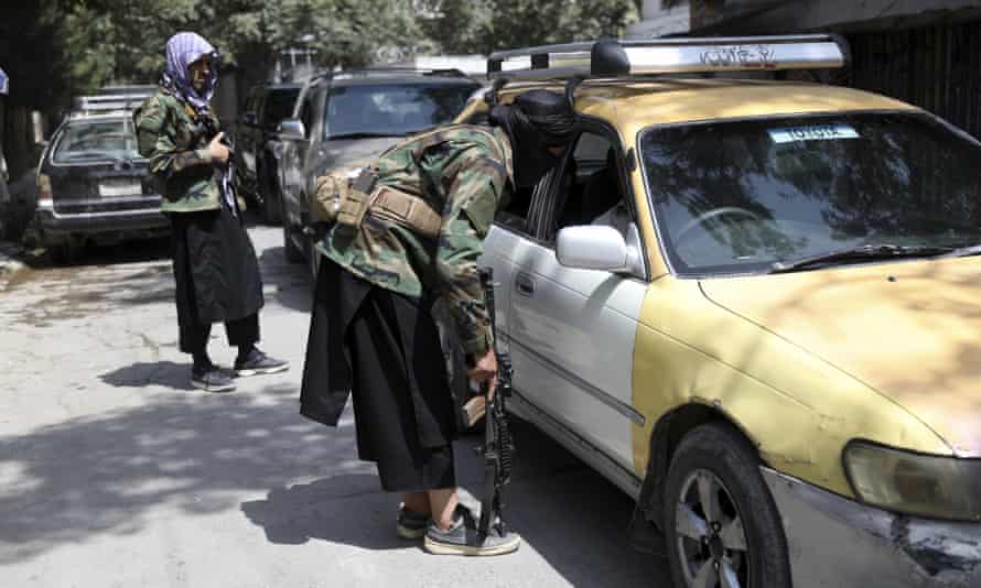 Các chiến binh Taliban khám xét một chiếc xe tại một trạm kiểm soát trên đường ở khu vực Wazir Akbar Khan của Kabul, Afghanistan,