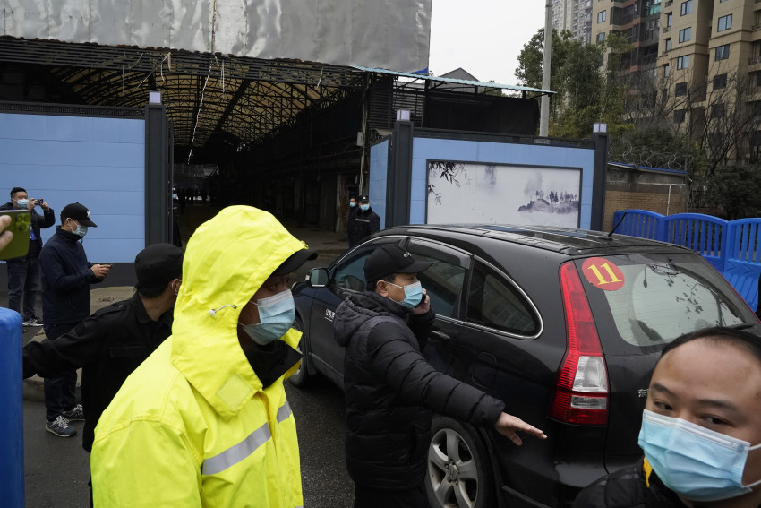 nhân viên an ninh dọn đường cho một đoàn xe của nhóm Tổ chức Y tế Thế giới vào Chợ Hải sản Hoa Nam 