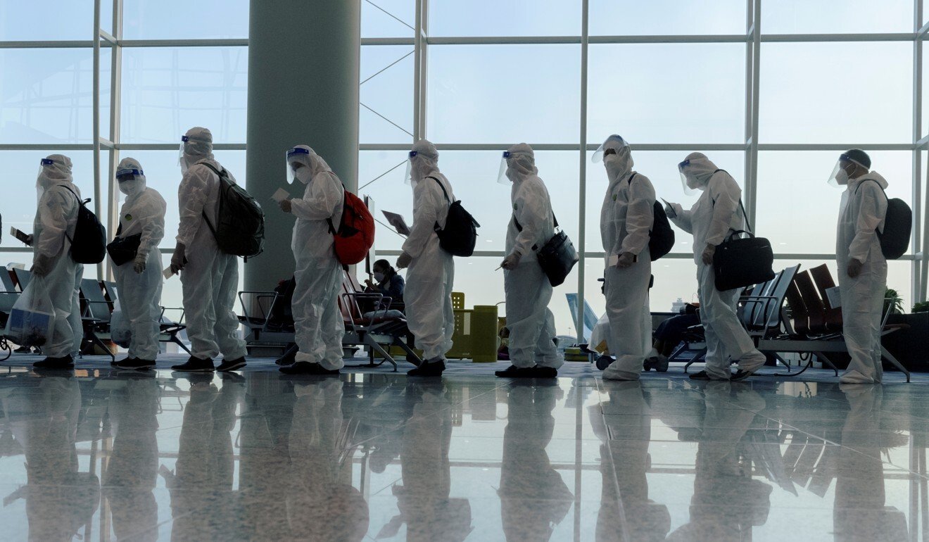 Hành khách mặc đồ bảo hộ xếp hàng lên chuyến bay quốc tế tại sân bay Hong Kong. Ảnh: Reuters