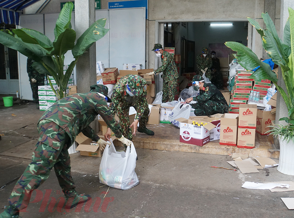 Đến khoảng 7g, hàng trăm túi quà đã được các chiến sĩ phân chia gồm lương thực phẩm, hàng thiết yếu,... xếp ngay hàng chờ xe đến để vận chuyển đến các hộ dân.