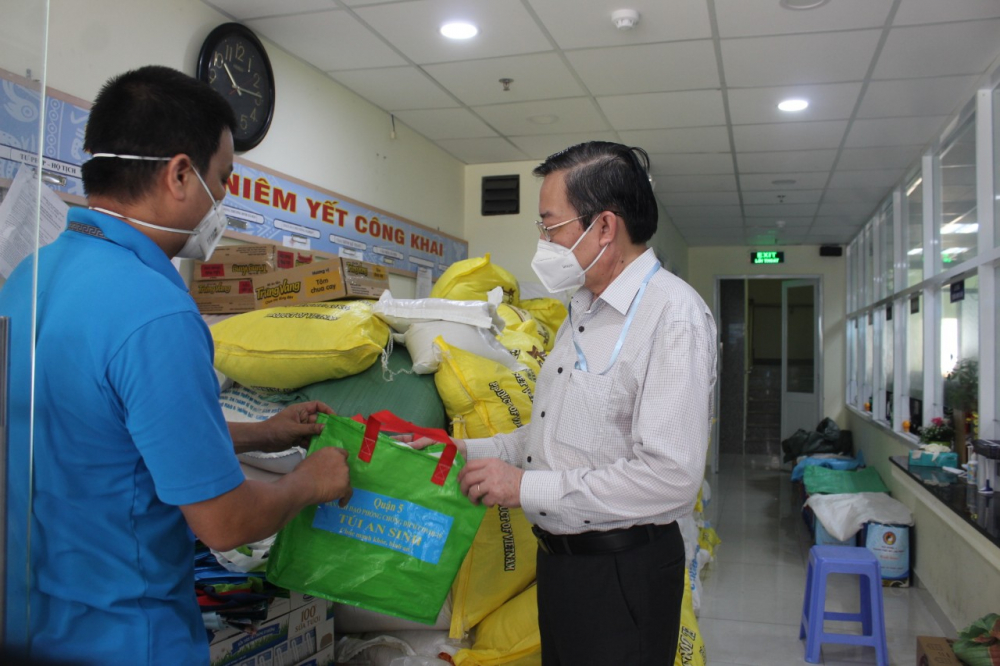 Ông Lê Hồng Sơn trao đổi với cán bộ Trung tâm An sinh địa phương về việc cung ứng túi an sinh hỗ trợ người có hoàn cảnh khó khăn bị ảnh hưởng vì COVID-19.
