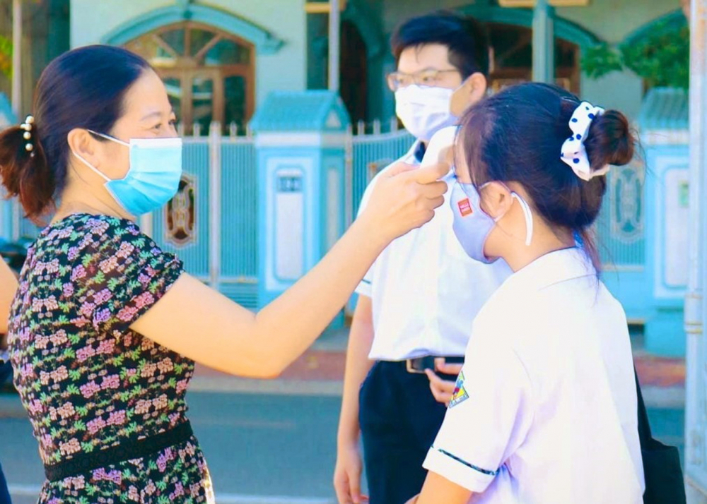 Học sinh Trường THPT Nguyễn Huệ, TP.Huế được kiểm tra thân nhiệt trước lúc vào trường - ẢNH: THUẬN HÓA