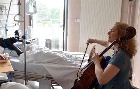 Nhạc sĩ và nhà trị liệu nghệ thuật người Pháp Claire Oppert chơi nhạc cho một bệnh nhân tại khoa chăm sóc đặc biệt của bệnh viện Sainte Perine vào ngày 11/7 ở Paris.