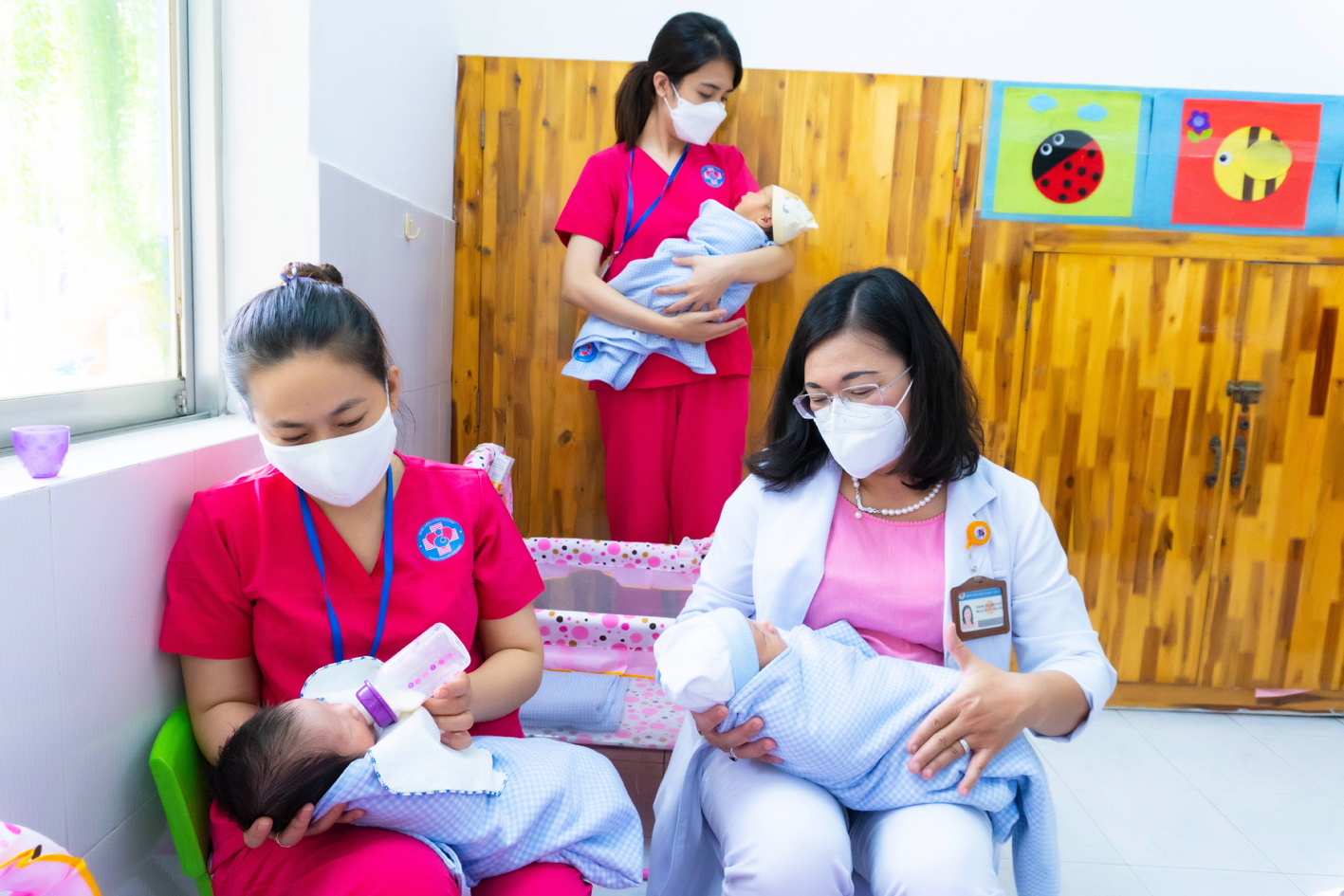Phó giáo sư - tiến sĩ - bác sĩ Hoàng Thị Diễm Tuyết (áo trắng - bên phải) và các bảo mẫu đang chăm sóc bé ở Trung tâm H.O.P.E