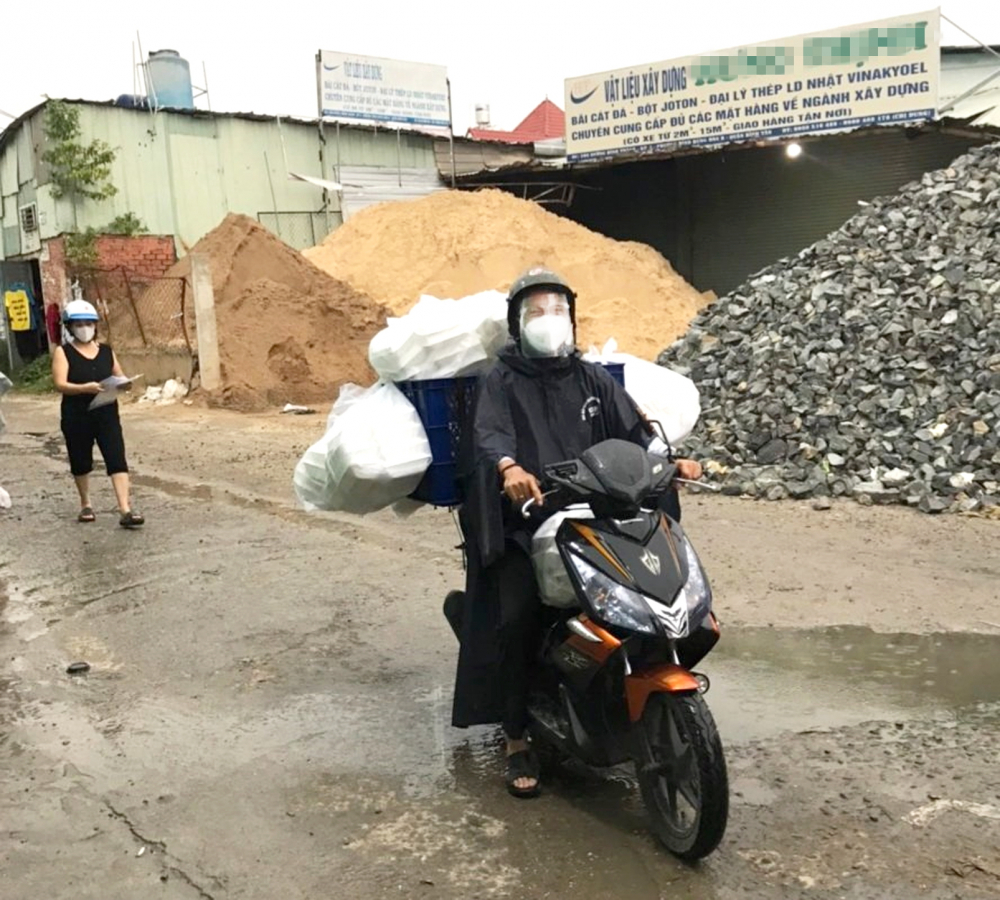 Ông Nguyễn Văn Cầu đội mưa chở hàng chục suất cơm cho người dân và cán bộ gác chốt  ở khu cách ly, phong tỏa