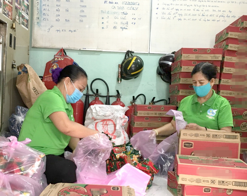 Bà Nguyễn Thị Bạch (trái) và cán bộ ở khu phố 5 chuẩn bị các túi quà để phát cho người dân gặp khó khăn khi phải ở yên trong nhà