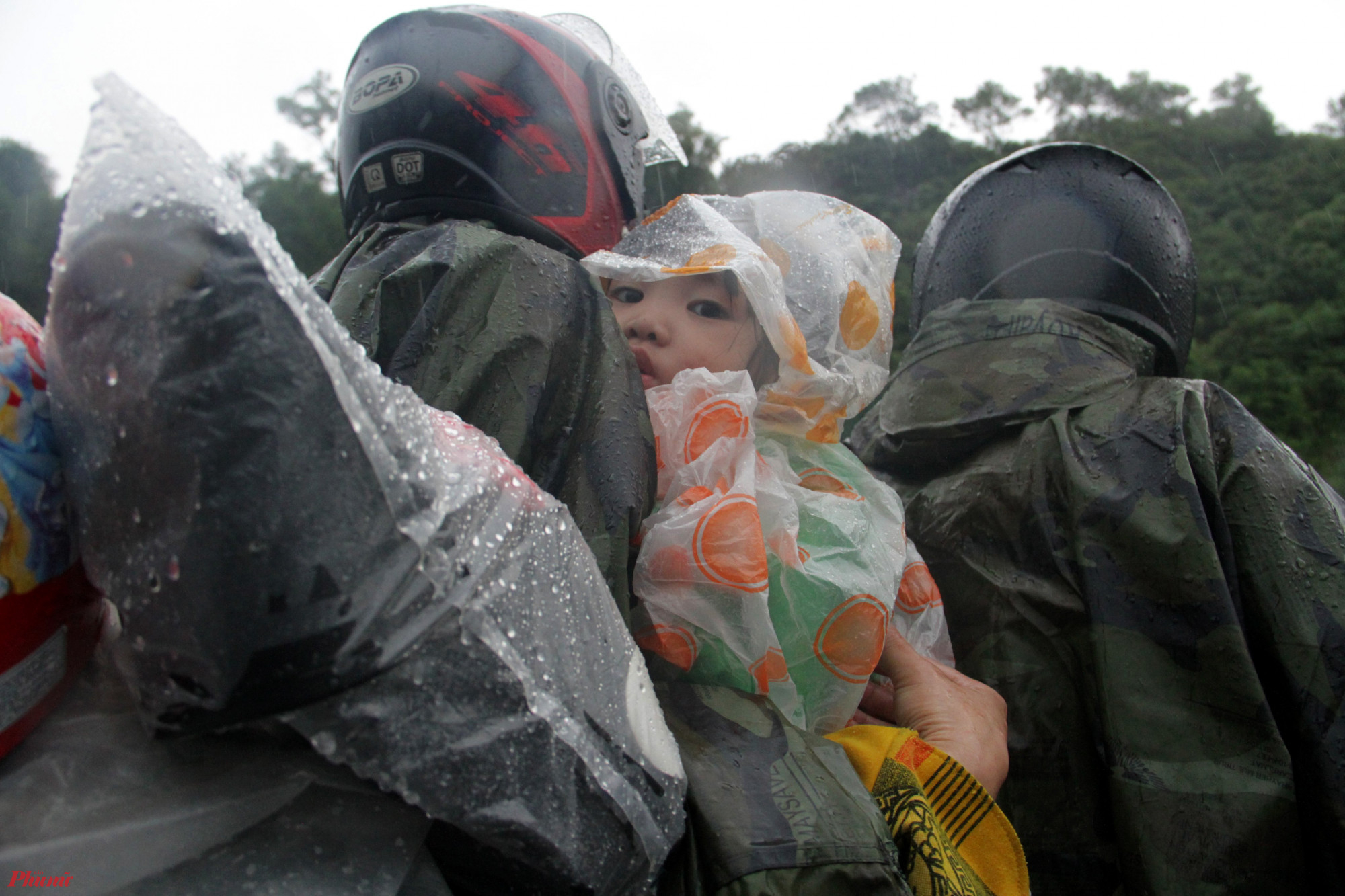 Nhiều đứa trẻ phải ngồi nép mình giữa bố mẹ trong chiếc áo mưa tiện lợi rộng thùng thình.