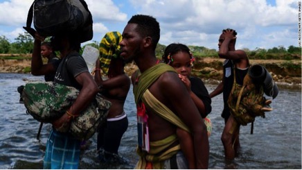 Những người di cư băng qua sông Chucunaque ở làng Bajo Chiquito, Panama, sau khi đi bộ 5 ngày qua Darien Gap.