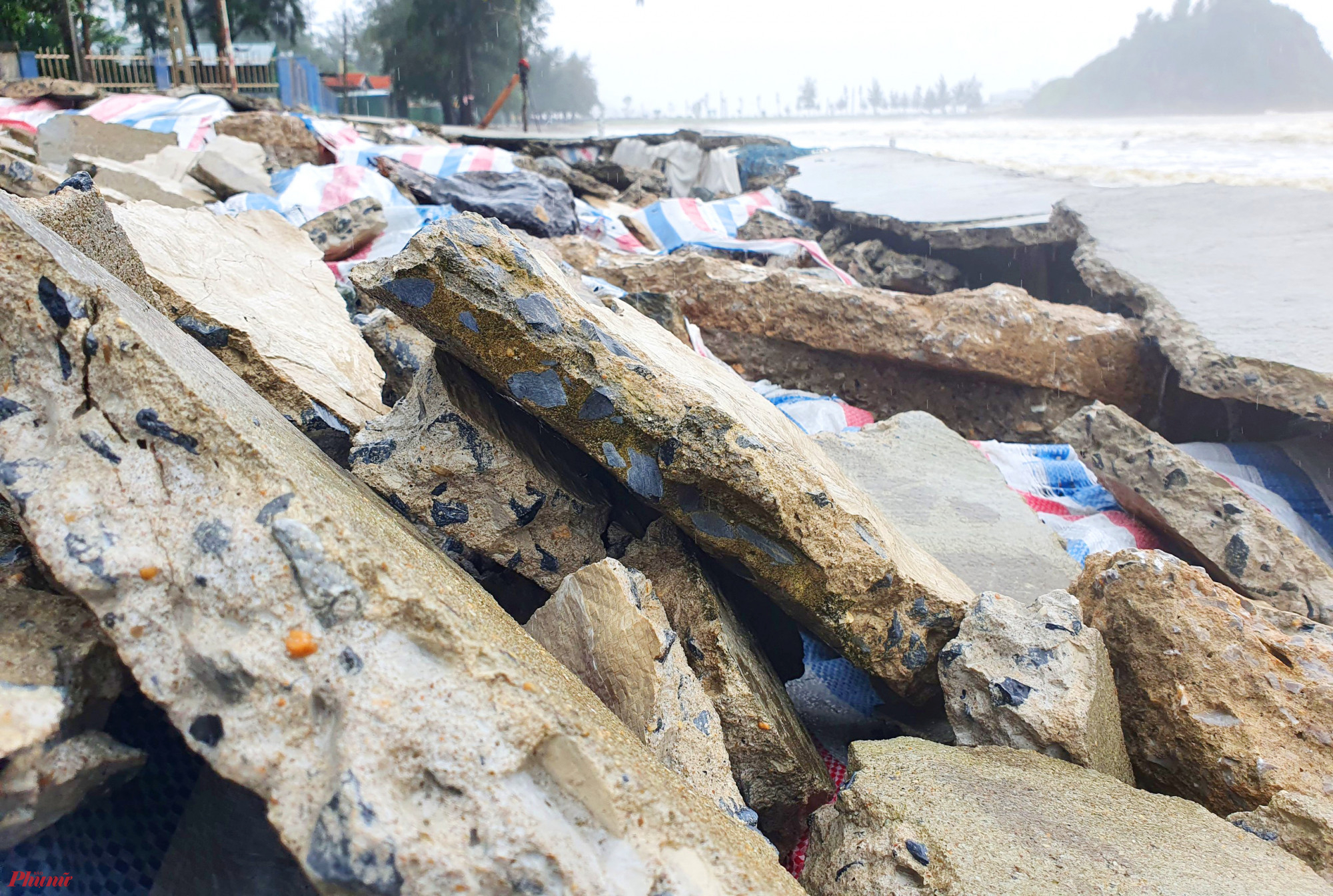 Nhiều mảng bê tông bị sóng hất văng lên bờ, chắn ngang lối dành cho người đi bộ ở ngay mặt tiền một số ki ốt kinh doanh của người dân.