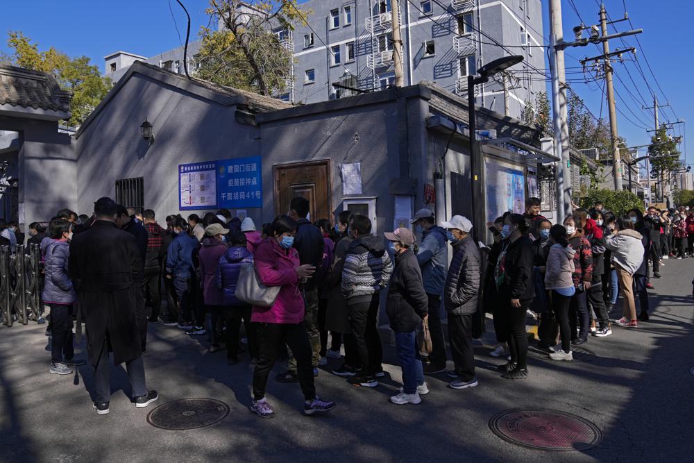 Người dân đeo khẩu trang, xếp hàng để tiêm mũi vắc xin tăng cường chống lại COVID-19 tại một điểm tiêm chủng gần khu dân cư ở Bắc Kinh hôm 22/10