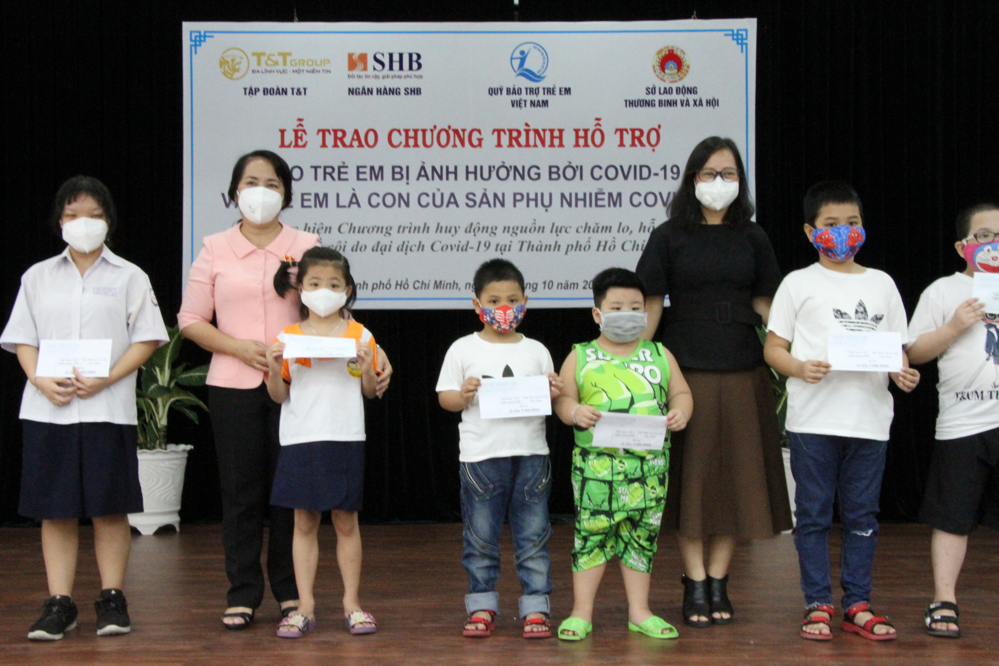 Bà Đặng Kim Yến, đại biểu Quốc hội, Bí thư Quận ủy quận 1 (trái) cùng đại diện Ngân hàng SHB trao hỗ trợ cho các em bị mồ côi cha mẹ do COVID -19