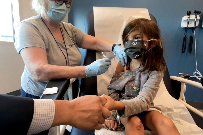 Một bé gái năm tuổi nắm tay bố khi được tiêm vắc-xin Pfizer trong khuôn khổ cuộc thử nghiệm tại Đại học Duke của Mỹ
