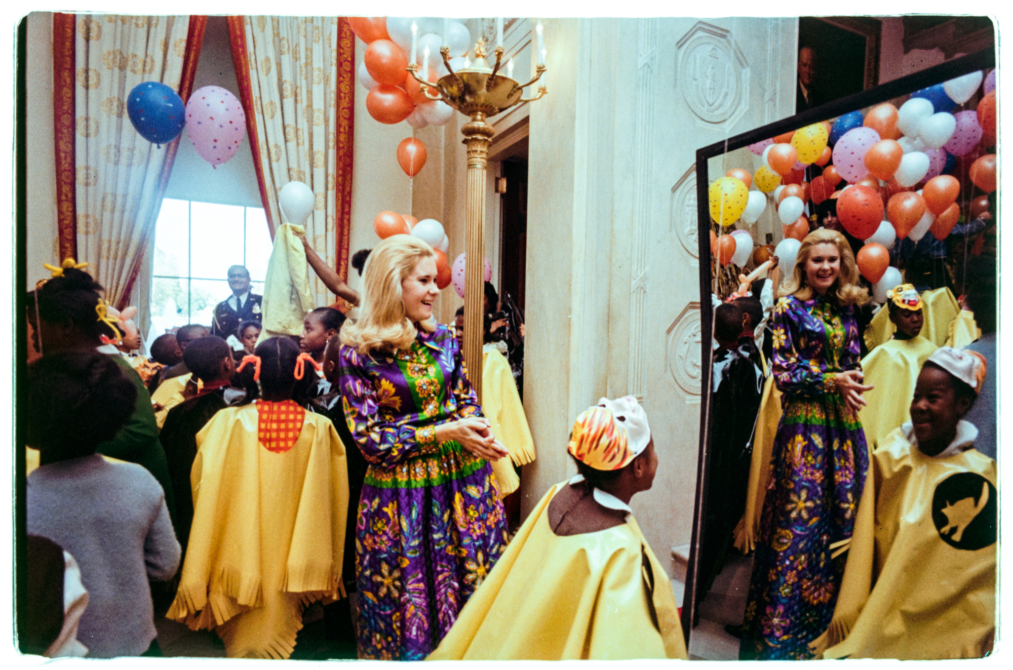 Con gái lớn của Tổng thống Richard M. Nixon, Tricia Nixon, mỉm cười khi một đứa trẻ mặc trang phục nhìn chằm chằm vào chiếc gương ngôi nhà vui nhộn trong Sảnh vào tại lễ hội hóa trang Halloween của Nhà Trắng. Sự kiện được tổ chức cho trẻ em địa phương ở khu vực Washington, DC.