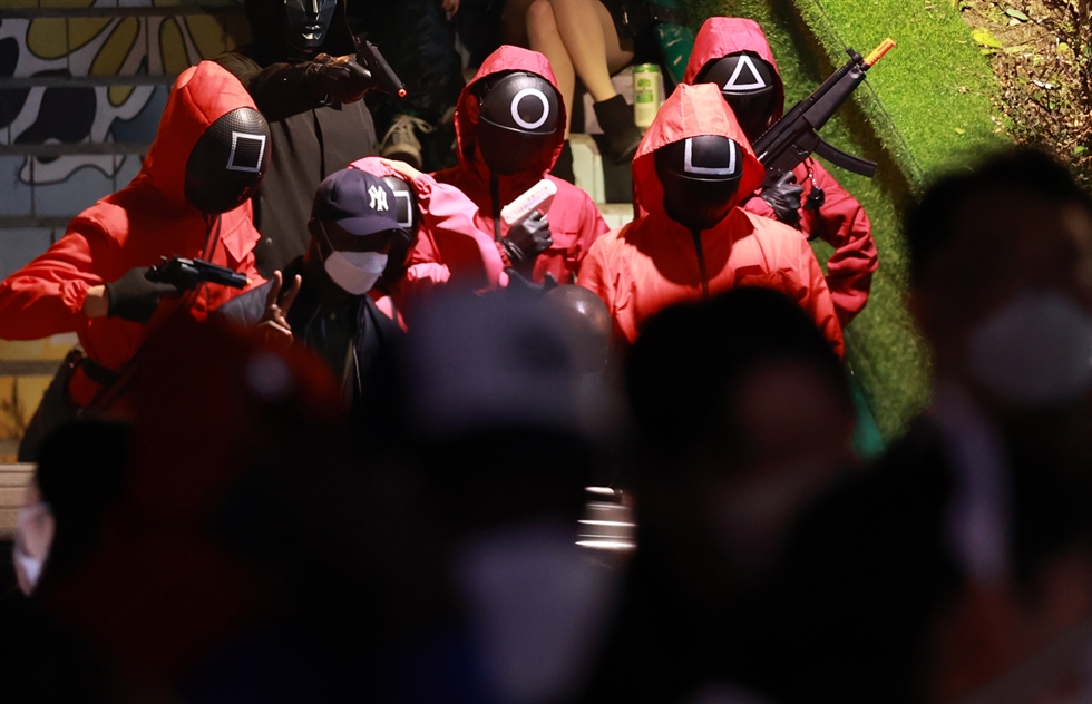 Trong ngày 31/10, nhiều bạn trẻ Hàn Quốc đã hóa thân thành những vệ sĩ đeo mặt nạ trong phim Squid Game, xuất hiện ấn tượng trên khu phố sầm uất Itaewon, Seoul.