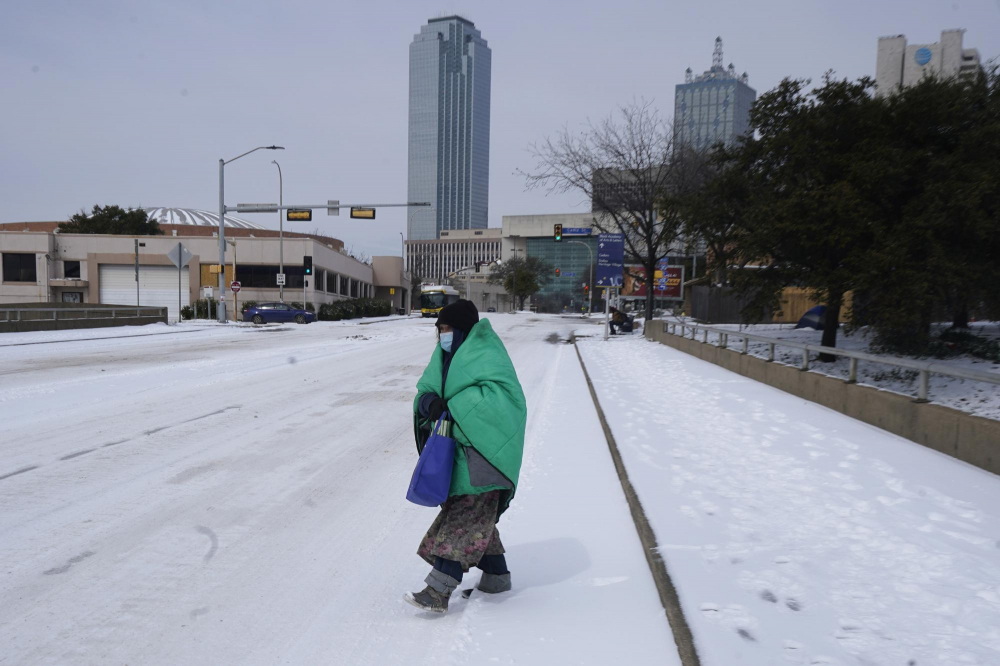 Một phụ nữ quấn chăn băng qua đường gần trung tâm thành phố Dallas vào ngày 20/2. Nhiệt độ giảm xuống mức một con số khi tuyết dày buộc các cửa hàng tạp hóa đóng cửa và du lịch hàng không đình trệ