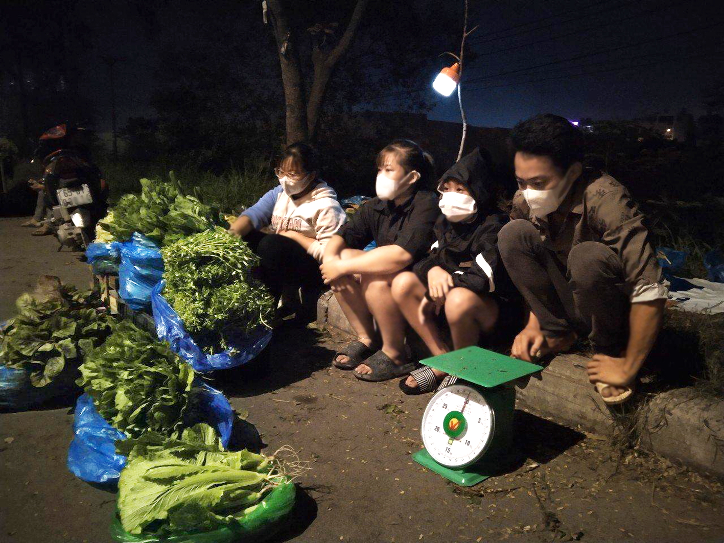 Bốn anh em chị N.X.V. ngồi chờ khách tới mua rau trong đêm