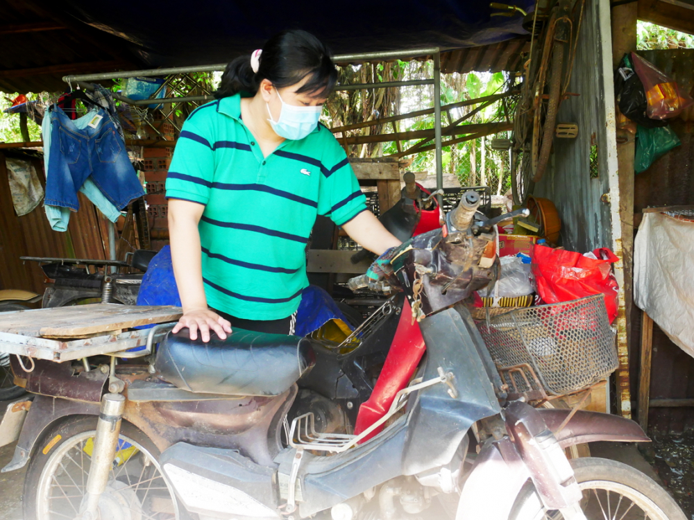 Nguyễn Thị Thanh Xuân bên chiếc xe máy cũ kỹ của ba để lại, khắc ghi những tháng ngày gian khổ