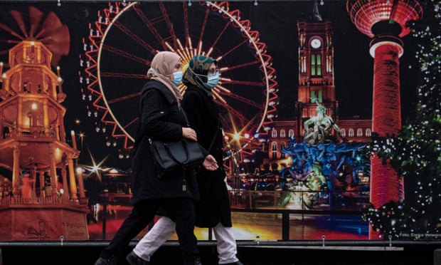 Những người phụ nữ đeo khẩu trang đi ngang qua khu chợ Giáng sinh truyền thống ở Berlin. Nghiên cứu toàn cầu cho thấy đeo khẩu trang là cách hiệu quả nhất để hạn chế nhiễm trùng Covid. Ảnh: John MacDougall / AFP / Getty Images