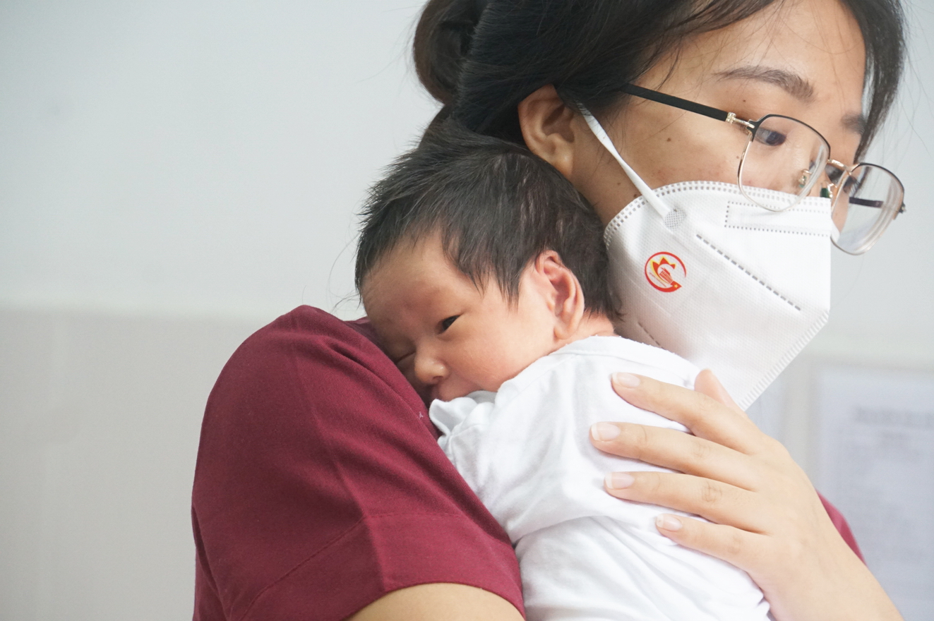 Tình nguyện viên tại Trung tâm H.O.P.E chăm sóc cho một em bé sơ sinh có mẹ mắc COVID-19 - ẢNH: PHẠM AN